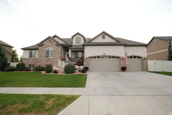 Stucco and brick exterior with arched windows, two-car garage, and landscaped front yard