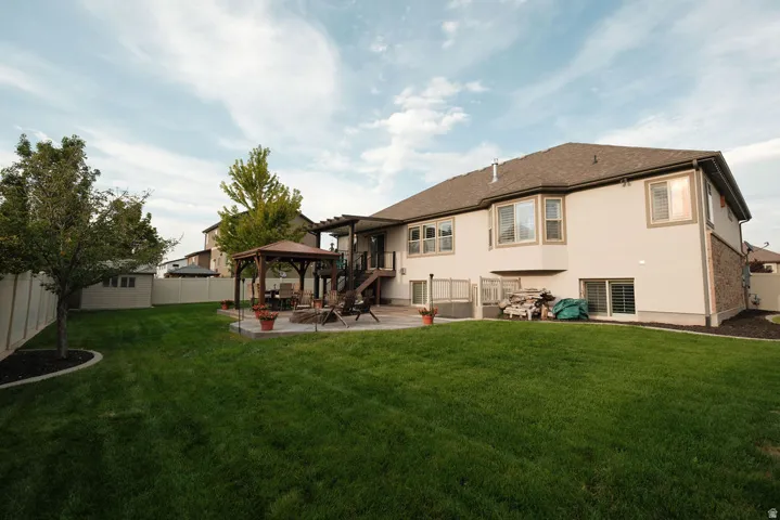 Expansive grassy backyard featuring a large patio, a built-in pergola, and a privacy fence
