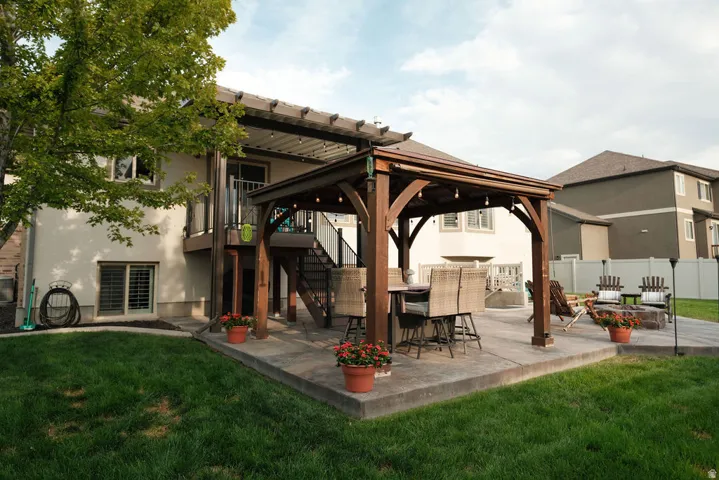 Expansive backyard with a large concrete patio, a wooden pergola, and a stone fire pit area