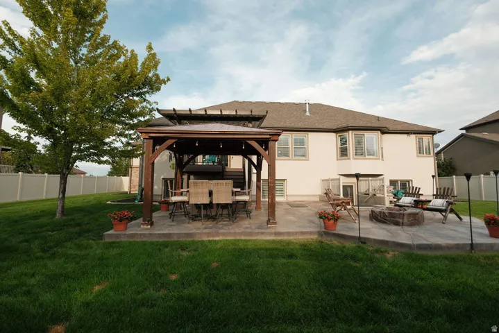 Expansive backyard featuring a concrete patio, a wooden pergola, a built-in fire pit, and a privacy fence