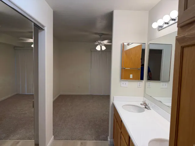 Dual vanity with integrated sinks, wood-finish cabinetry, and overhead bar lighting