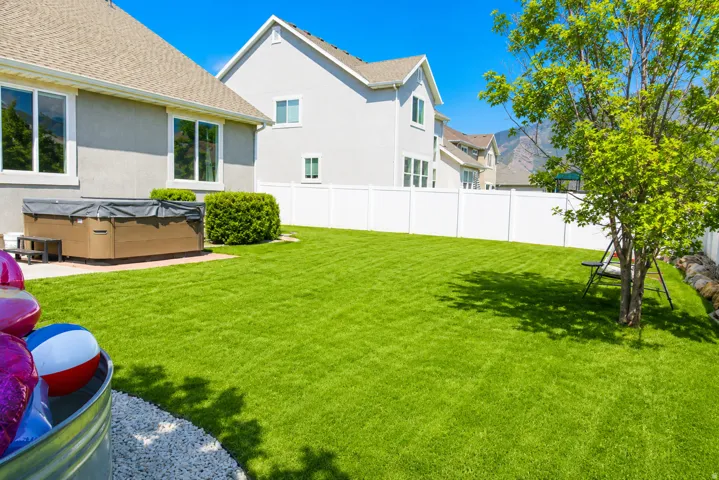 Expansive lawn with a white privacy fence and established trees