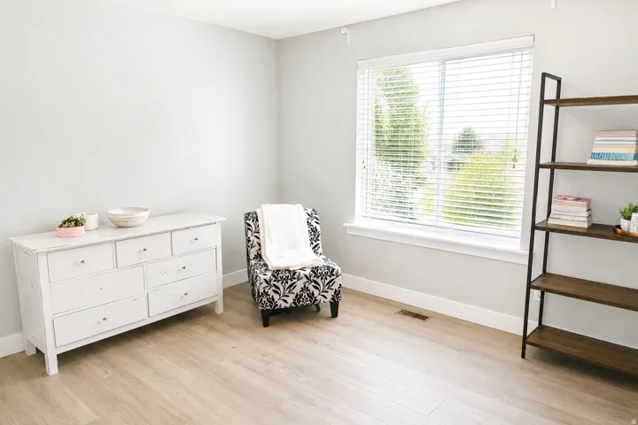 Wood-finish flooring with a large window and blinds