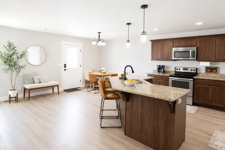 Open-concept kitchen and dining area featuring wood-finish flooring, recessed lighting, pendant lighting, and stainless steel appliances