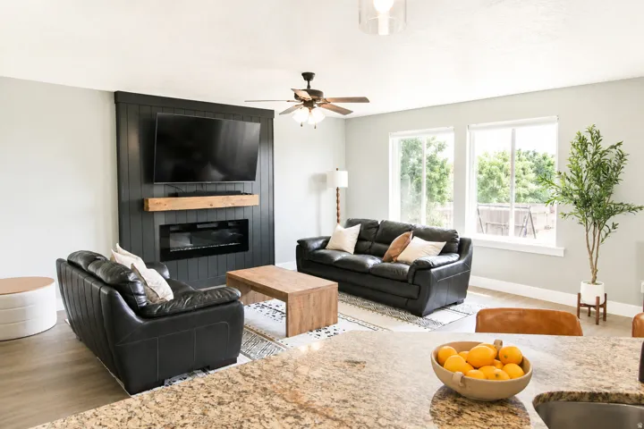 Living area featuring wood-finish flooring, a ceiling fan, and multiple large windows