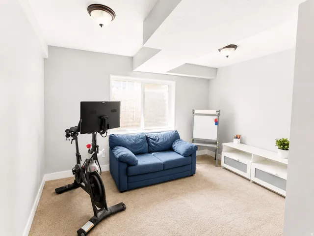 Carpeted room with light gray walls, a single window with blinds, and two flush-mount ceiling lights