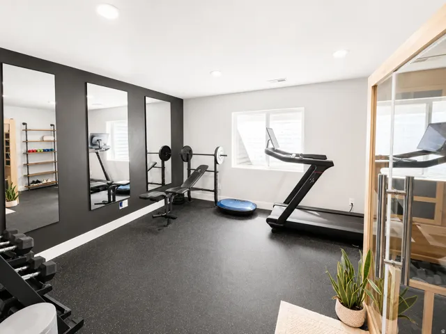Dedicated fitness space featuring rubber flooring, recessed lighting, and multiple full-length mirrors