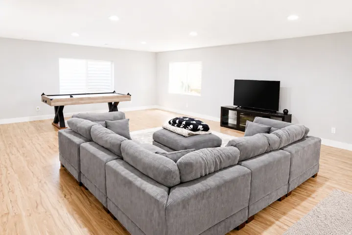Spacious recreation area featuring wood-finish flooring, recessed lighting, and multiple windows