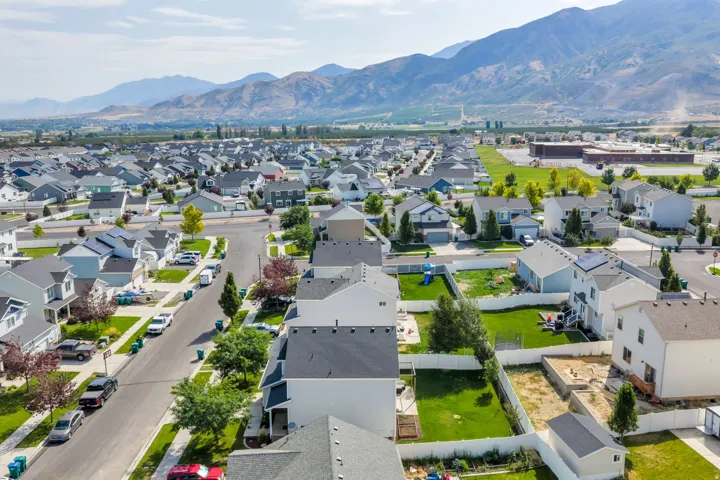 Aerial view showcasing a newly developed residential neighborhood with modern single-family homes featuring manicured lawns, mature landscaping, and gray composite roofing