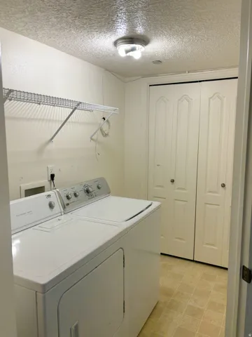Laundry area with wire shelving, bi-fold closet doors, and light-toned flooring