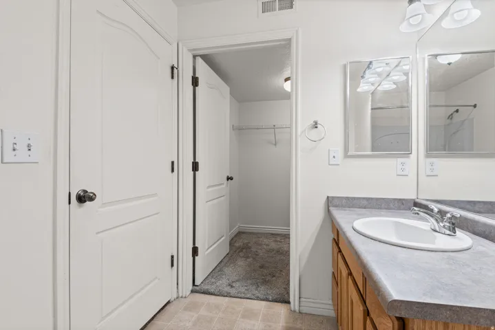 Vanity with a single basin sink, chrome faucet, and integrated counter space