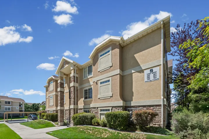 Three-story stucco exterior with stone accents, covered parking, and manicured landscaping