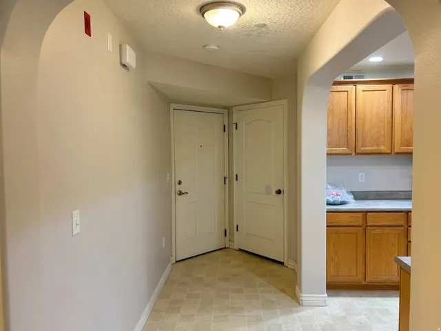 Arched doorway leading to a space with wood cabinetry and light-colored countertops