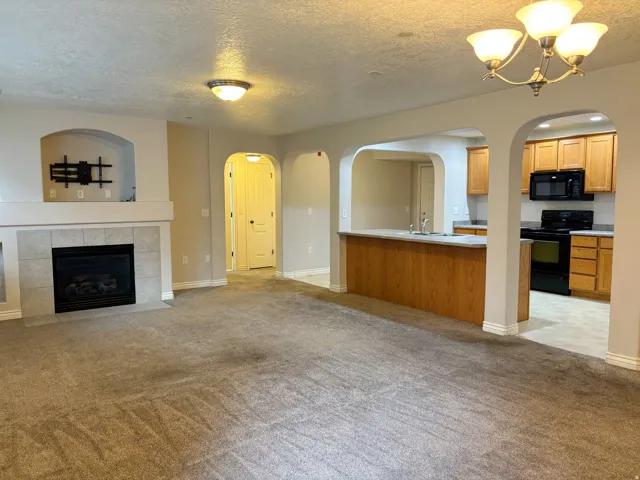 Living area featuring an arched fireplace with a tiled surround, recessed shelving, and soft carpeting