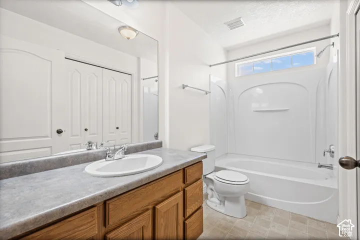 Vanity with wood cabinetry and countertop, integrated sink with chrome faucet, large wall mirror, and a full bathtub with overhead shower
