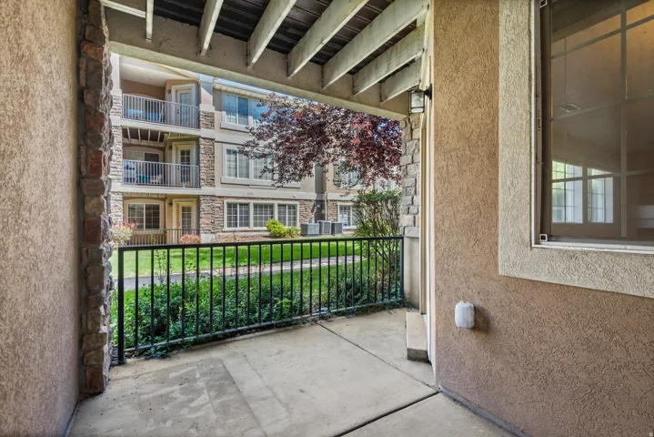 Covered concrete patio with black metal railing