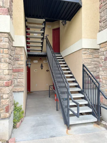 Exterior featuring stone column accents, stucco siding, and a red entry door