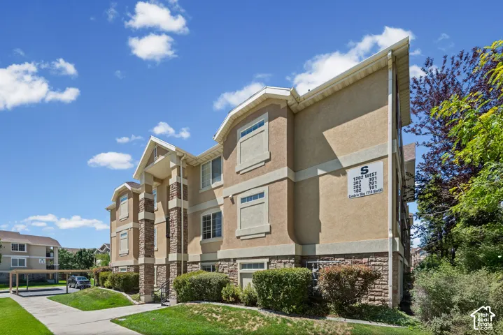 Three-story stucco exterior with stone accents, covered parking, and manicured landscaping