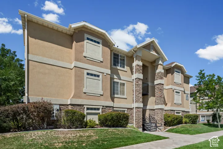 Multi-story building featuring a stucco exterior, stone accents, and a prominent entry with a black metal handrail