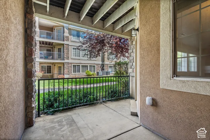 Covered concrete patio with black metal railing