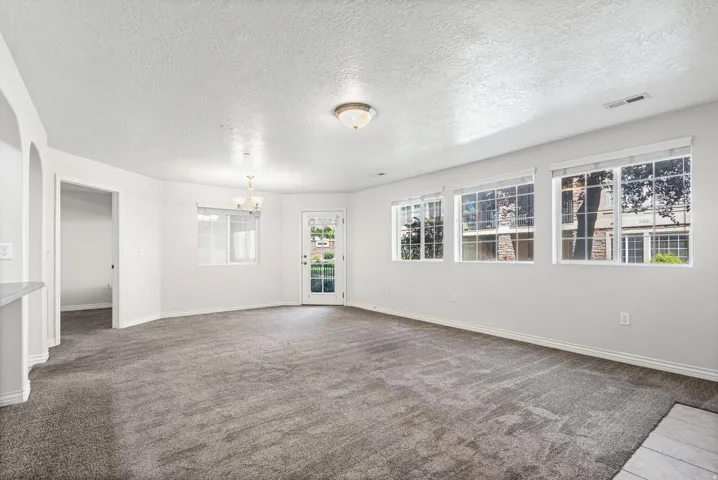 Expansive living area with neutral carpeting and multiple large windows
