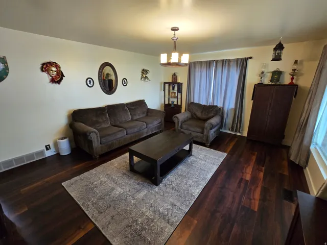 Wood-finish flooring throughout, complemented by a suspended chandelier, and window treatments