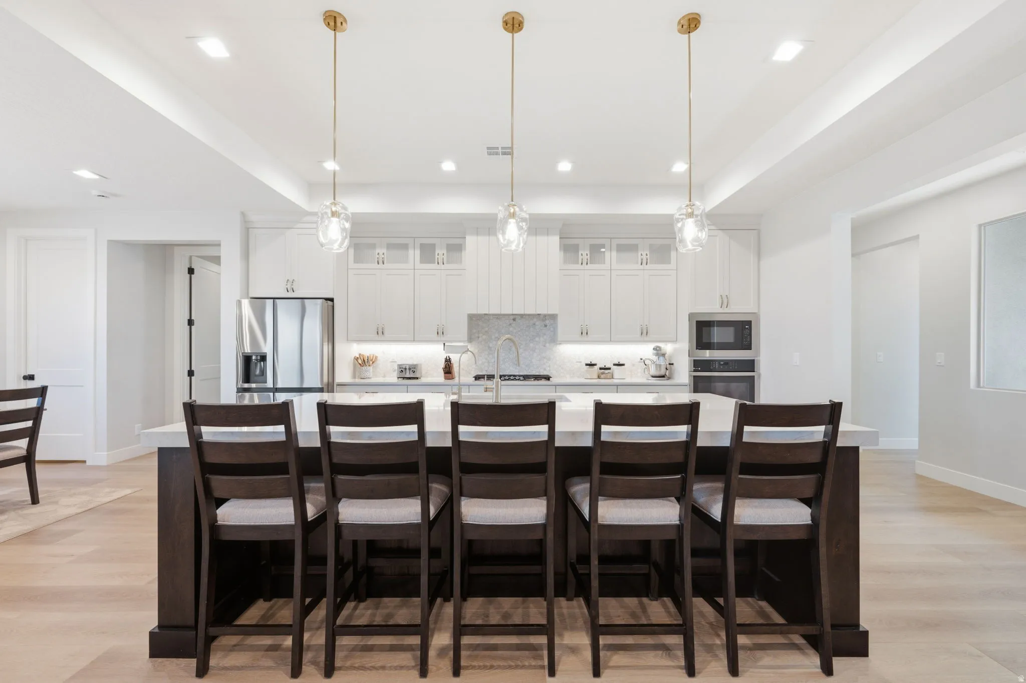 Spacious kitchen featuring a large island, white cabinetry, stainless steel appliances, and LVP wood-finish flooring
