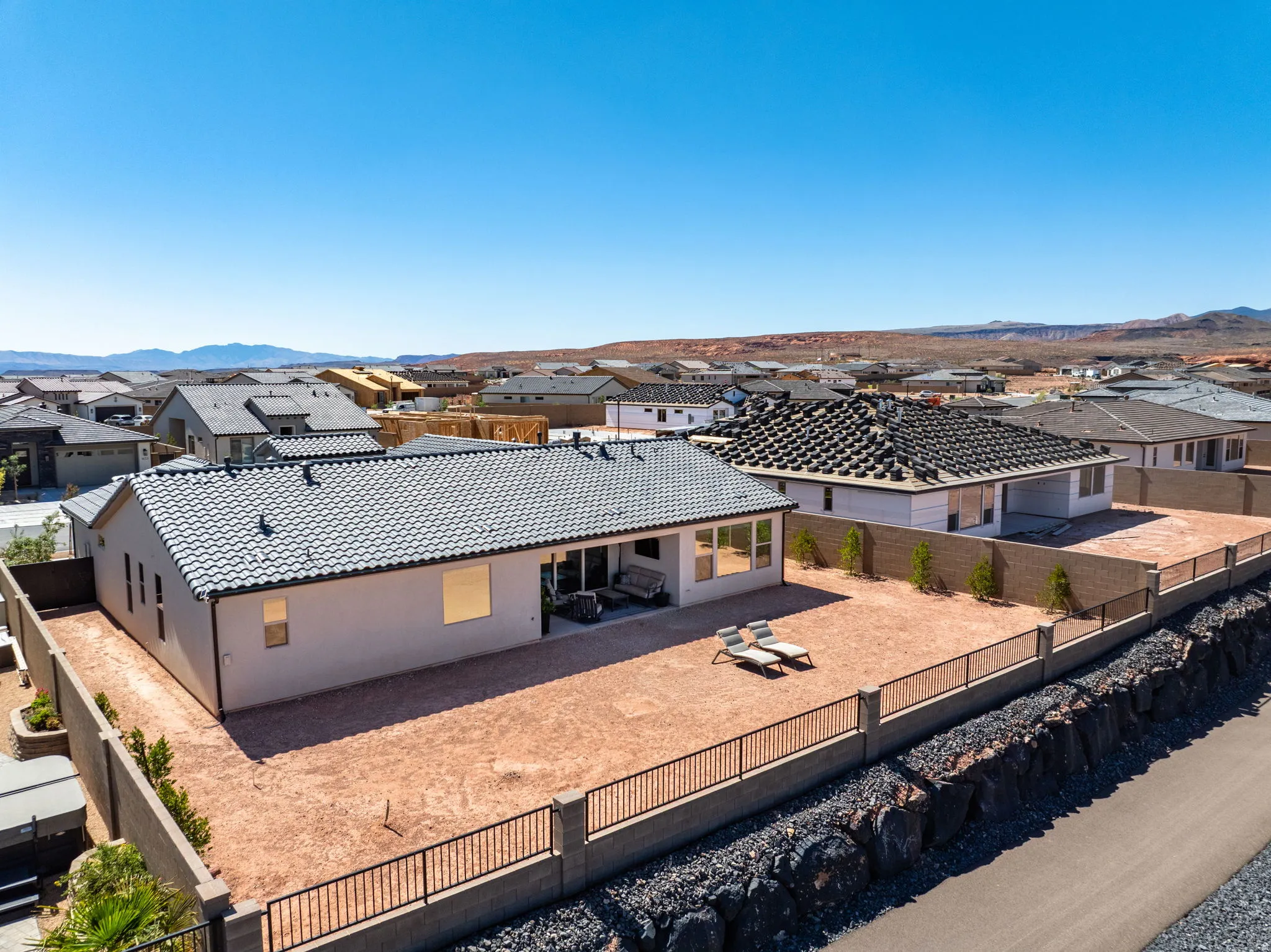 Expansive backyard space with block and wrought iron perimeter fencing,