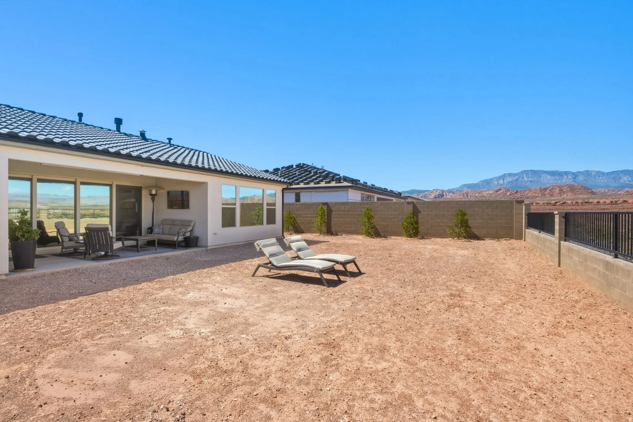 Expansive backyard with a covered patio, extensive hardscaping, and a block wall perimeter