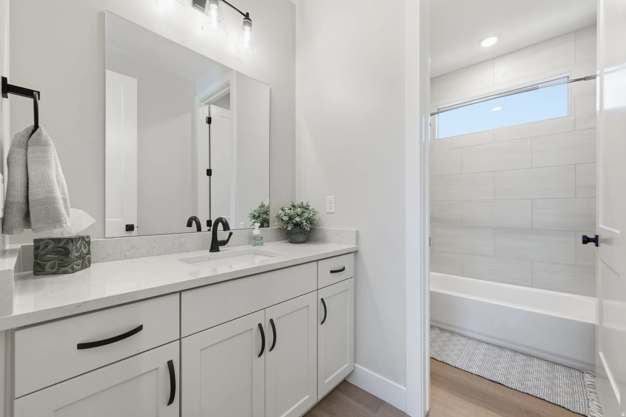 Bathroom featuring a quartz vanity with matte black hardware, a rectangular undermount sink, and a large mirror