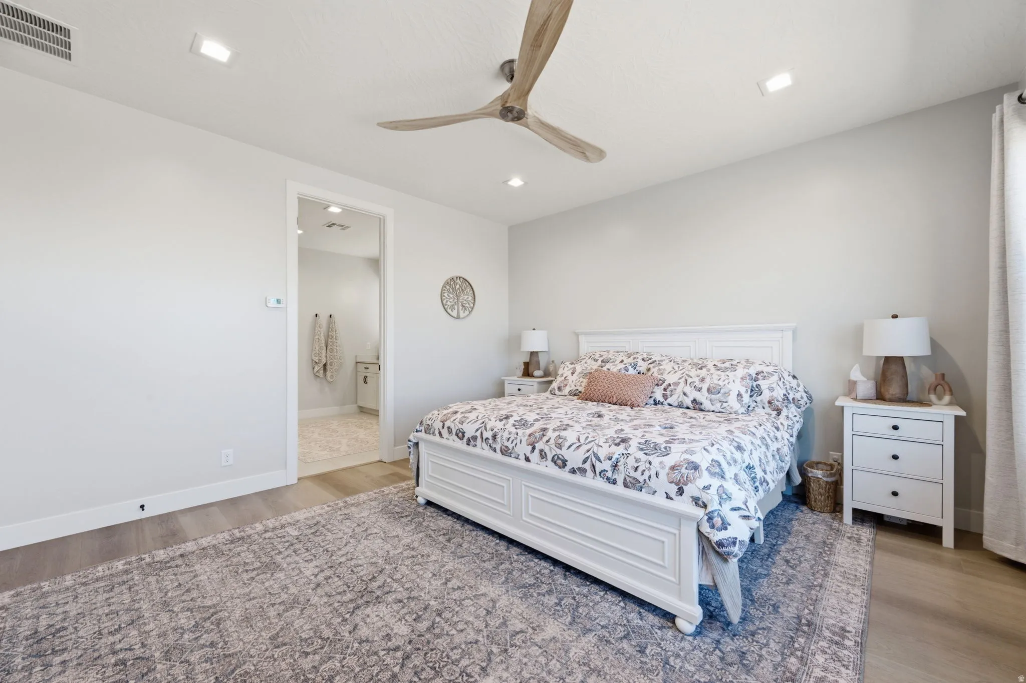 Vaulted ceiling with a wood-finish ceiling fan, recessed lighting, LVP wood-finish flooring, and a white vanity with an undermount sink and faucet