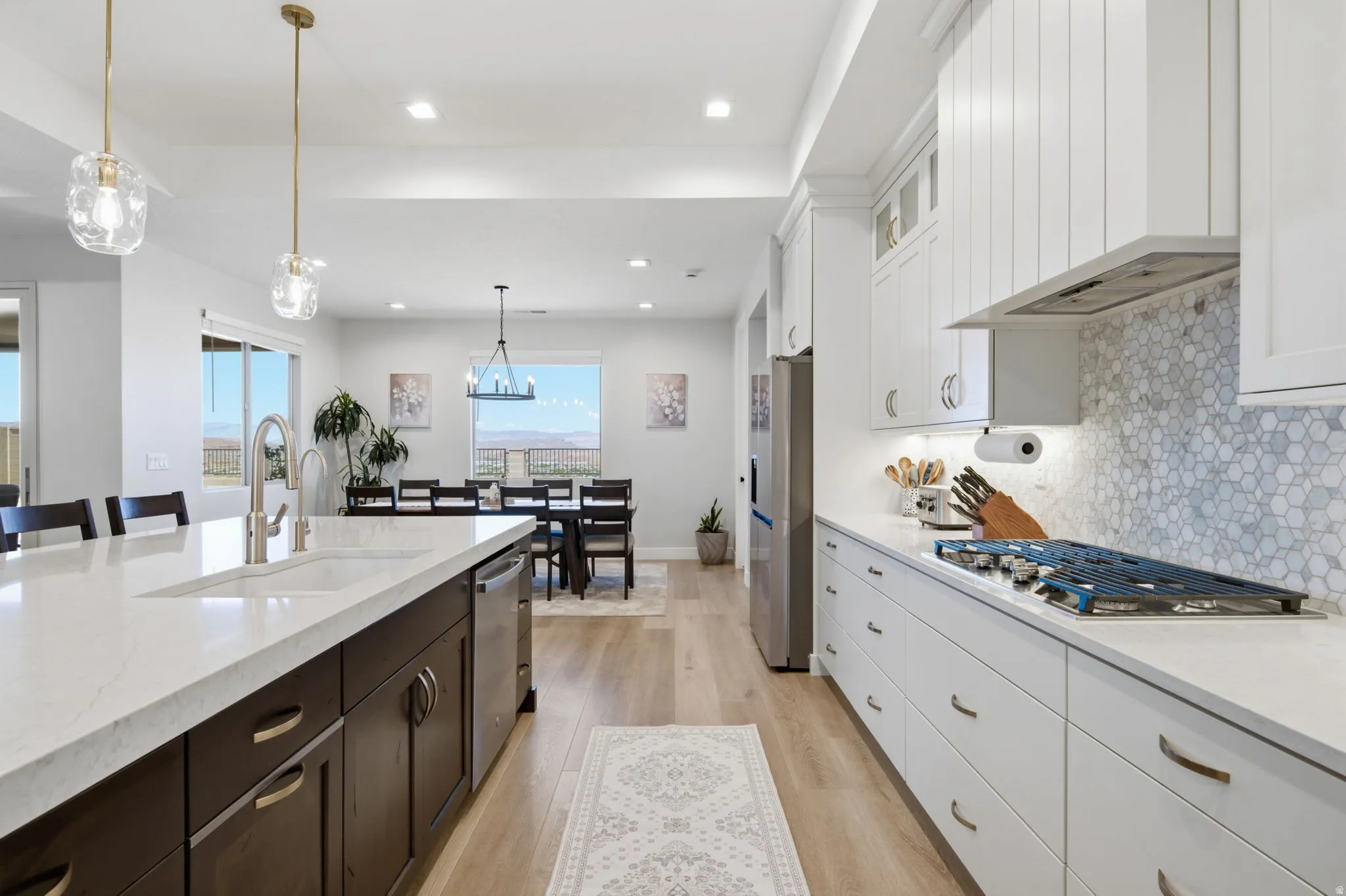 Open-concept kitchen featuring an expansive island with an integrated sink, pendant lighting, and stainless steel appliances