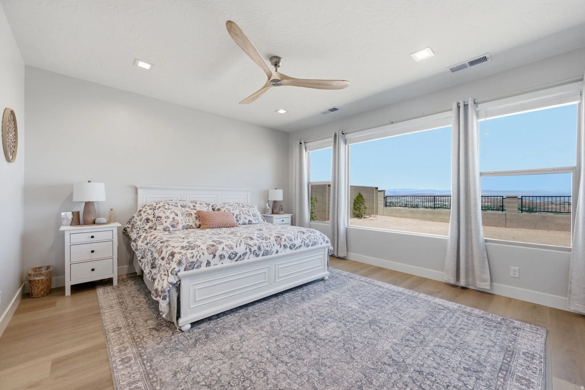 Spacious Primary bedroom featuring LVP wood-finish flooring, a vaulted ceiling, and recessed lighting