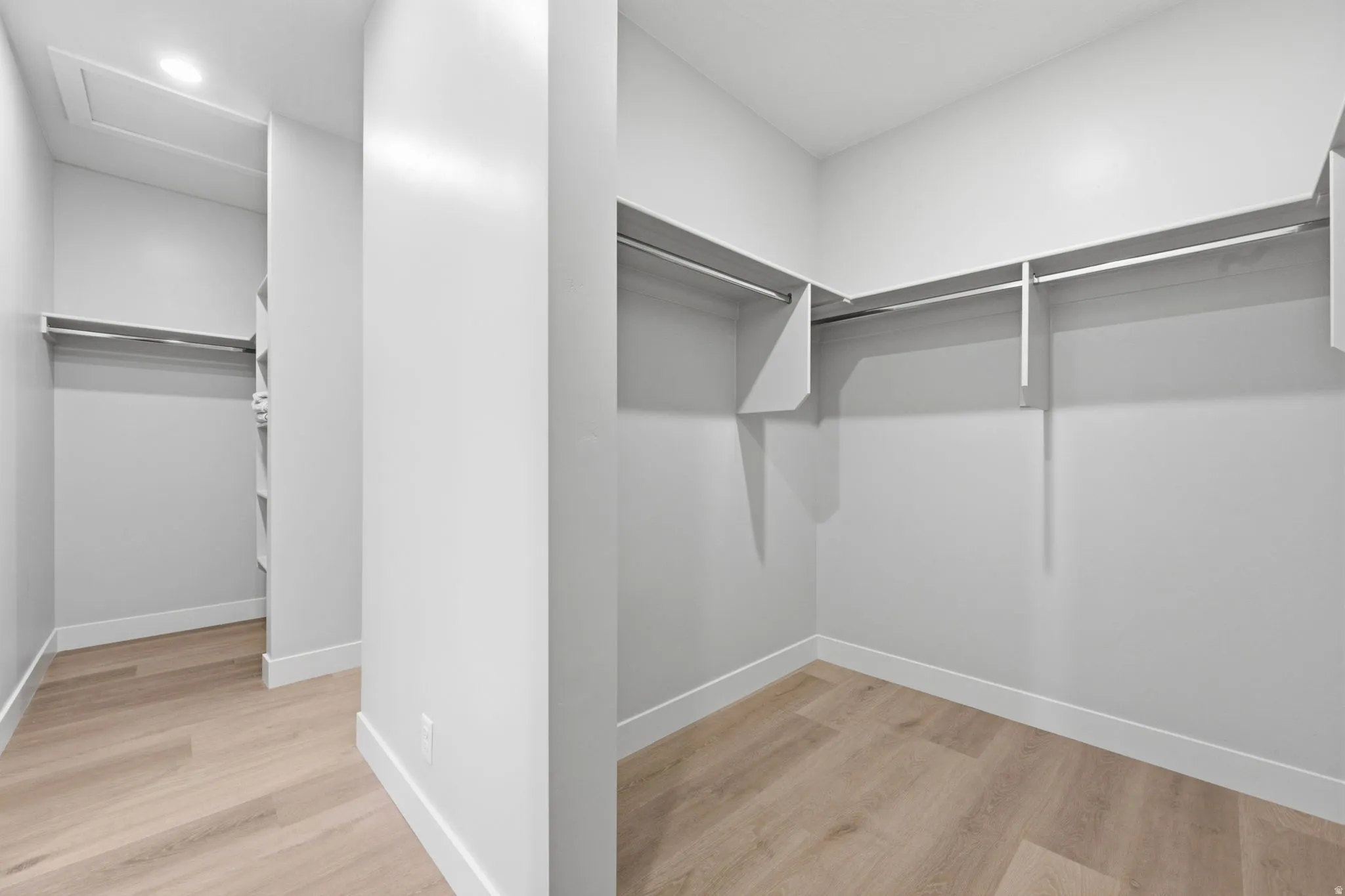 Walk-in closet with integrated shelving, multiple hanging rods, and LVP wood-finish flooring