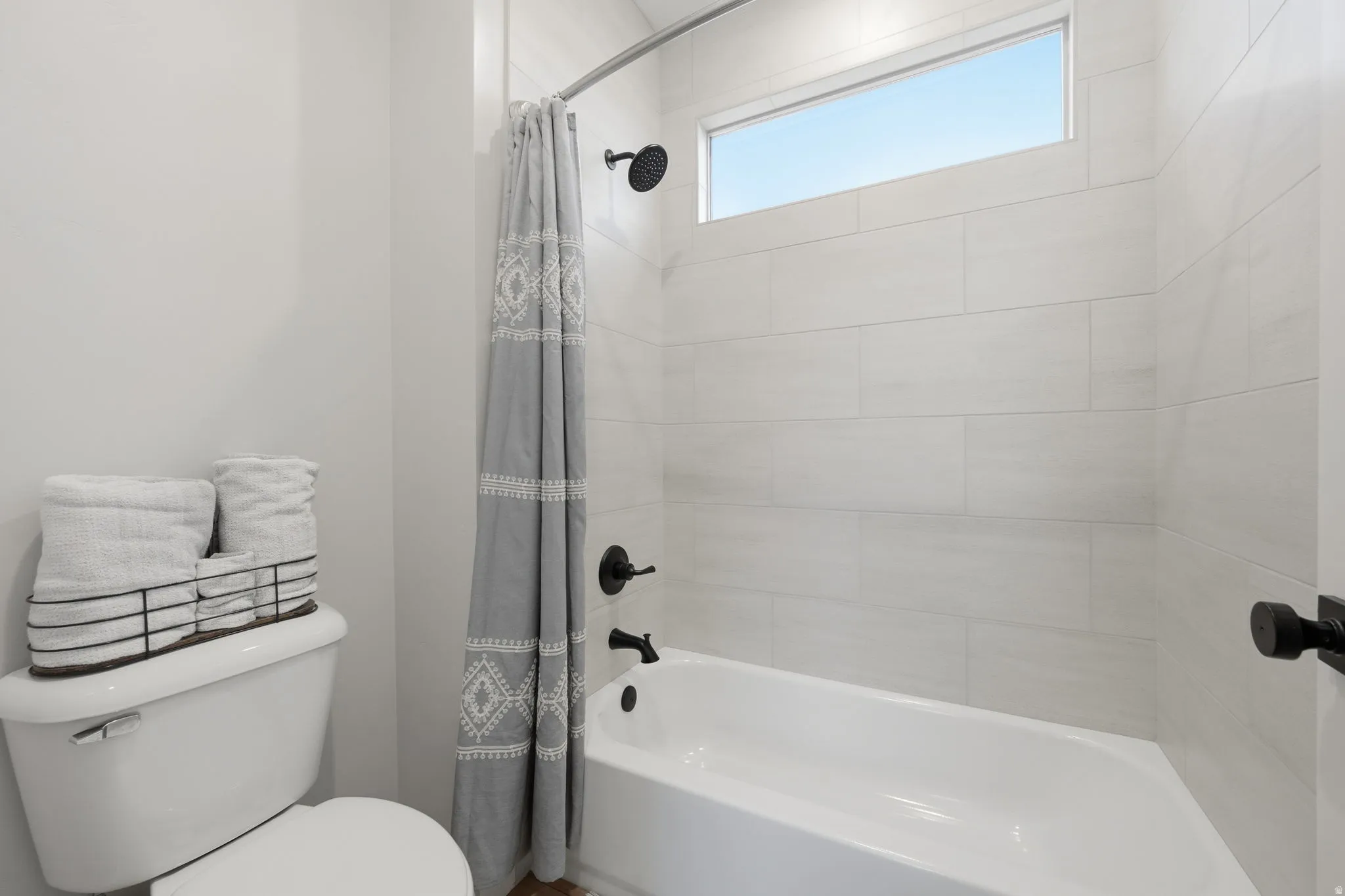 White subway tile shower surround with a built-in tub and matte black fixtures