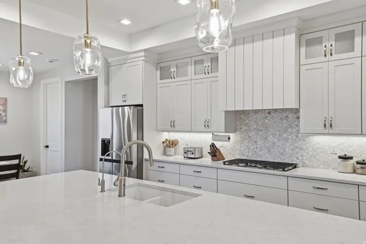 Kitchen featuring a large island with an undermount sink, stainless steel appliances, light-toned cabinetry, Range hood / vented out, honeycomb tile backsplash, and recessed lighting