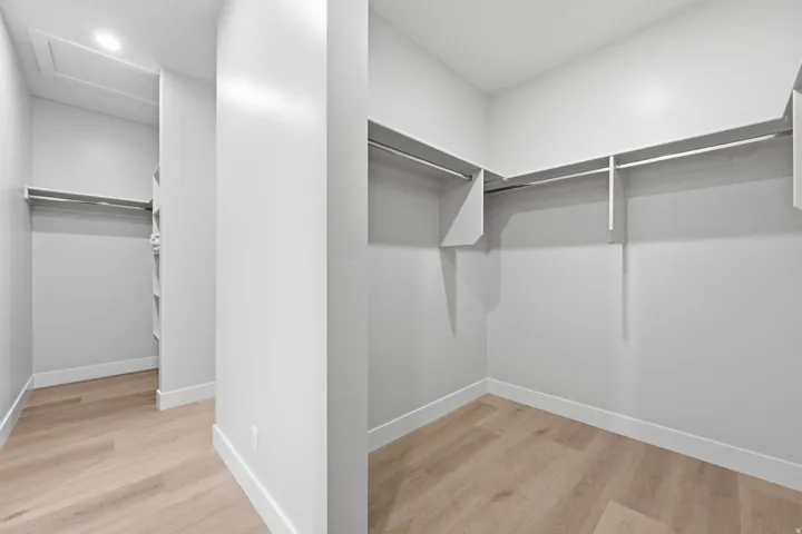 Walk-in closet with integrated shelving, multiple hanging rods, and LVP wood-finish flooring