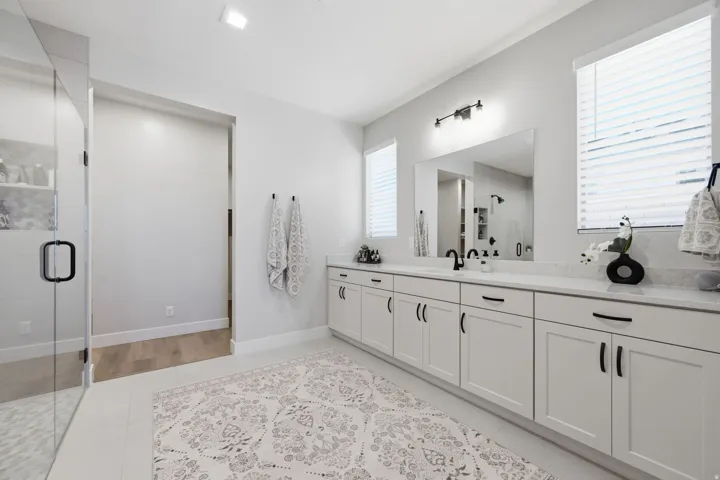 Spacious bathroom featuring a frameless glass shower enclosure, a vanity with white cabinetry, and a large mirror