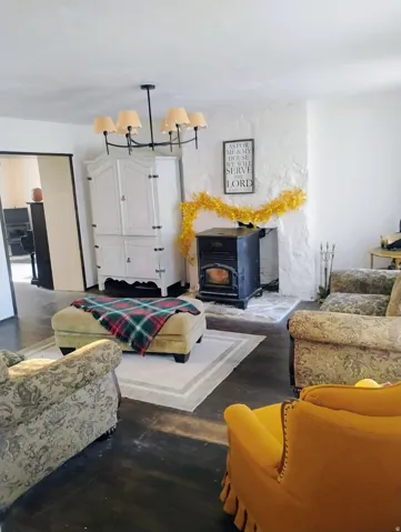 Stucco fireplace with hearth, dark wood-finish flooring, and a multi-light chandelier
