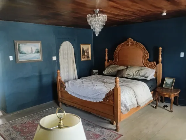 Distressed wood-finish ceiling, crystal chandelier, arched doorway, and light wood-finish flooring