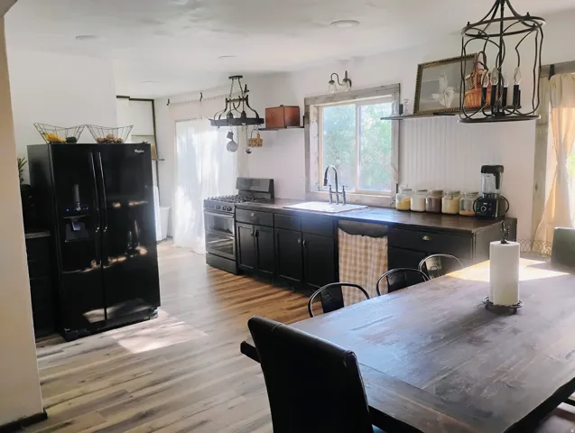 Spacious kitchen featuring wood-finish flooring, dark-toned cabinetry, stainless steel appliances, and a gas range