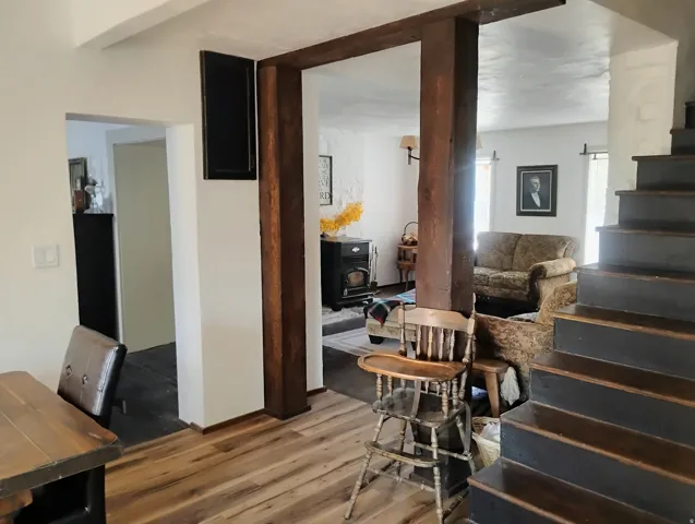 Wood-finish flooring throughout, exposed wood support beams, painted wood stairs, and white walls