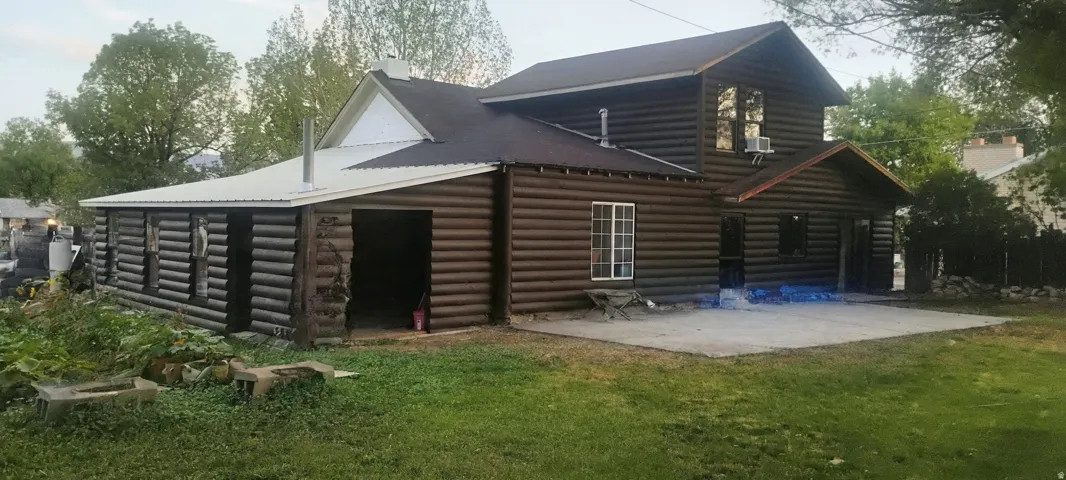Log-style exterior with multiple windows and a concrete patio