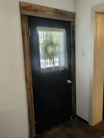 Black door with a window, framed by rustic wood trim