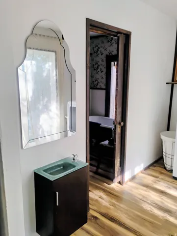 Wall-mounted dark wood-finish vanity with a glass basin and chrome faucet