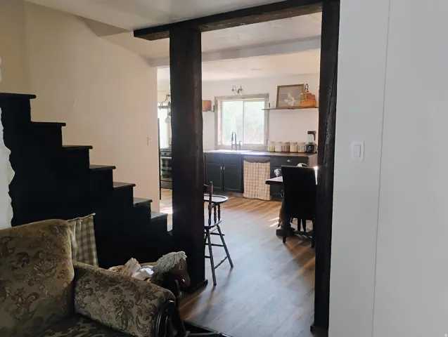 Dark-stained wood beams and trim frame an opening to the kitchen