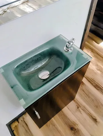 Floating vanity with a glass basin, chrome faucet, and wood-finish flooring