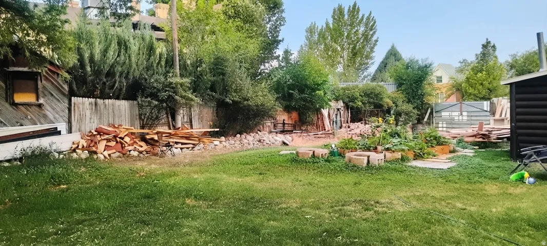 Expansive green lawn with mature perimeter landscaping and a wooden privacy fence