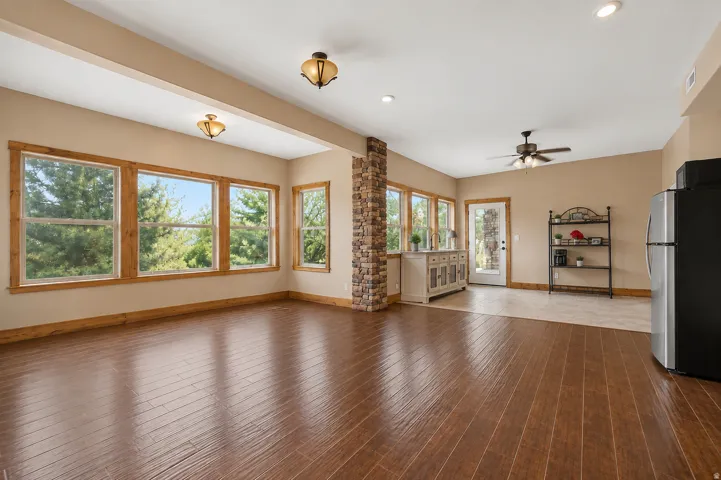 Wood-finish flooring throughout, complemented by a stone-clad column and abundant natural light from multiple windows