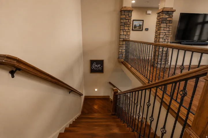 Level 1 to 2... Wood-finish flooring on stairs and landing, wrought iron balusters, stone-clad columns, and wood handrails
